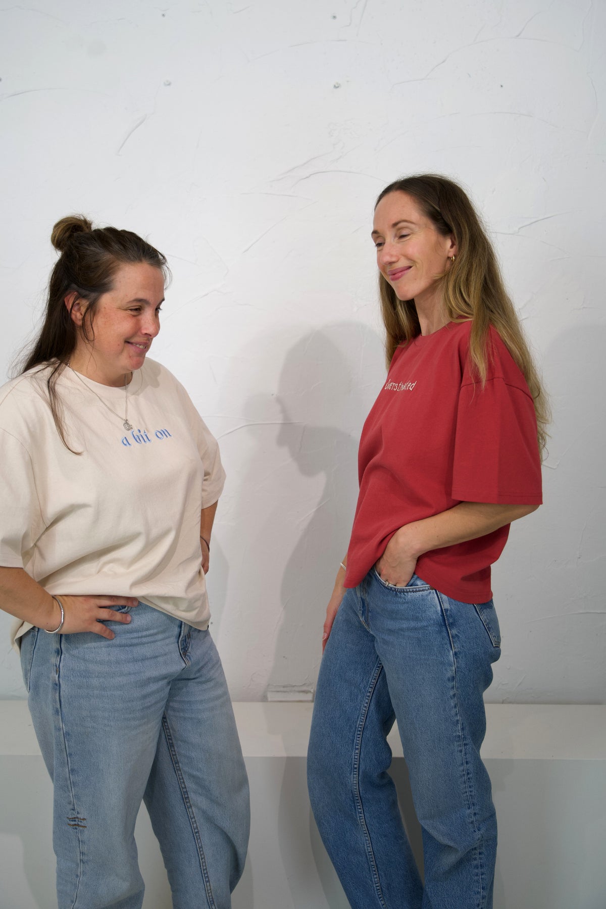 Two adults wearing Oat and Cabernet Momenta women’s tees, showing their relaxed fit.